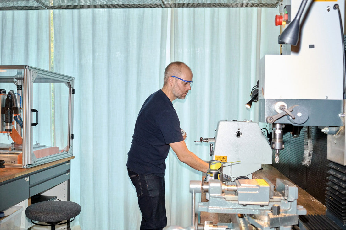 Aarke workshop in Stockholm: staff in safety glasses at a lathe and milling machine, building prototypes and samples.