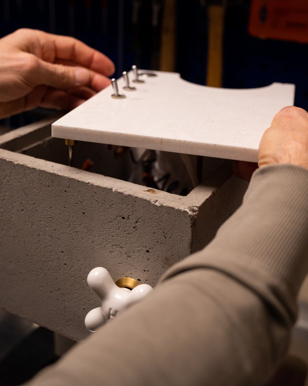 Hands fit the white top plate onto the cast concrete housing of the AnZa, porcelain knob in view.