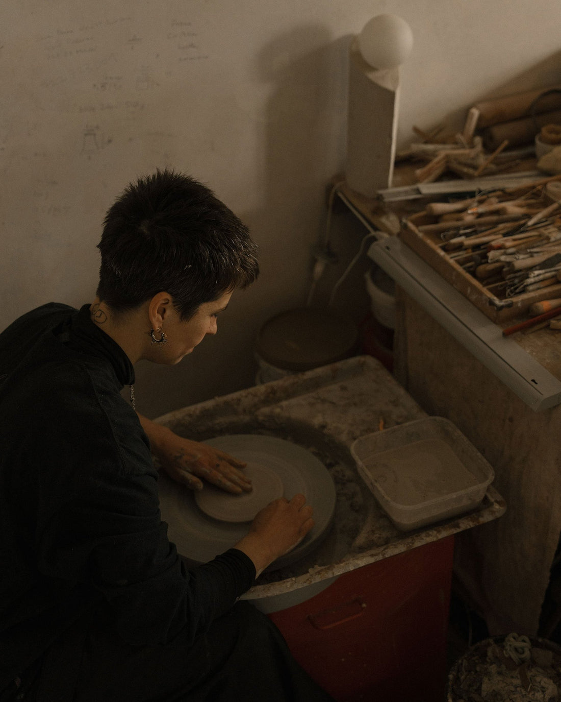 Elise Gettliffe trims a ceramic piece on the potter's wheel, her tools close at hand.