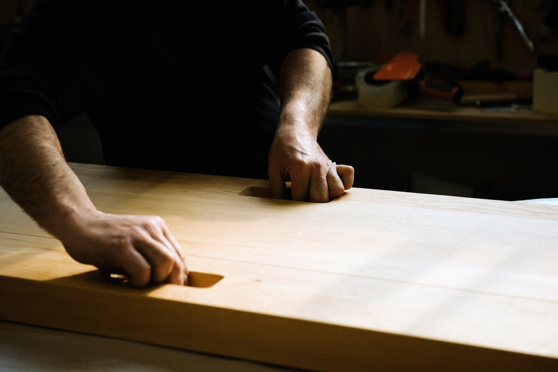 Joinery near Padua: a carpenter's hands in the dovetail recesses of a solid wood top for the Max Table.