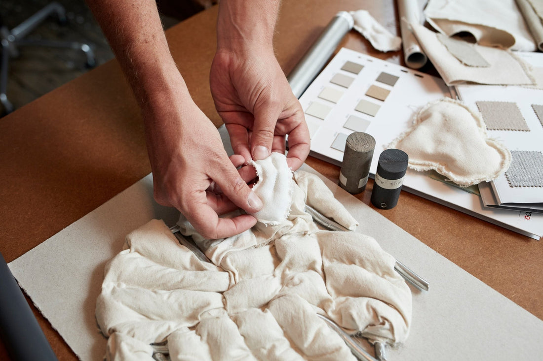 Hands shaping a quilted upholstery model beside colour samples.