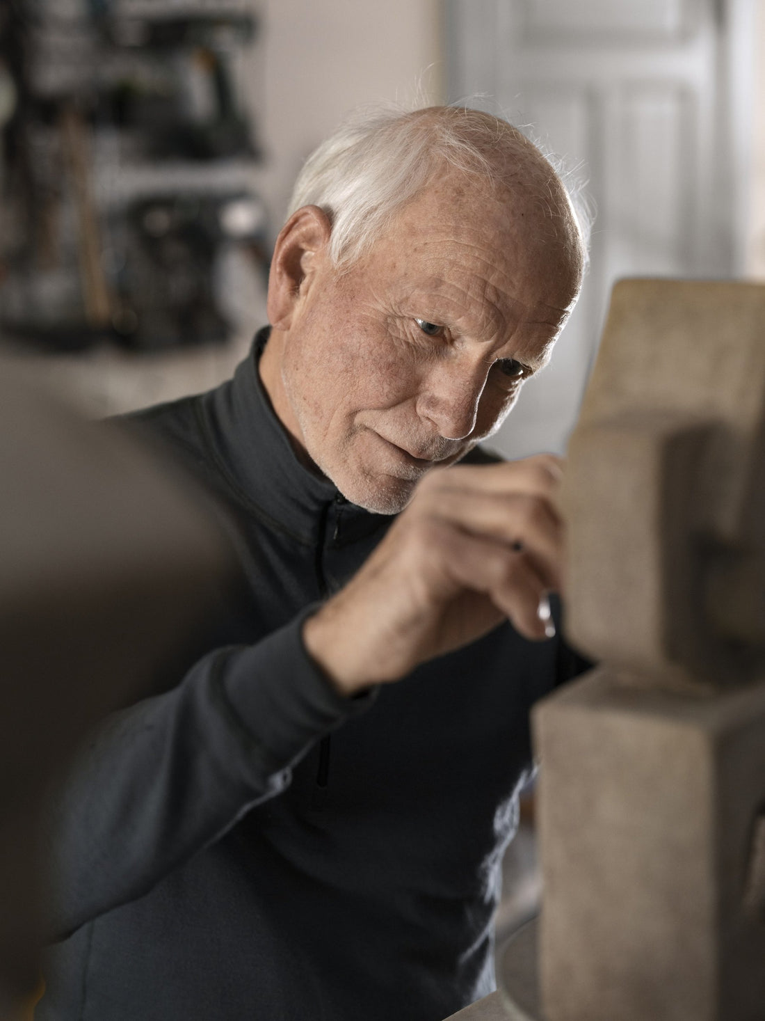 An artist working on a sculpture with a modelling tool in his studio.