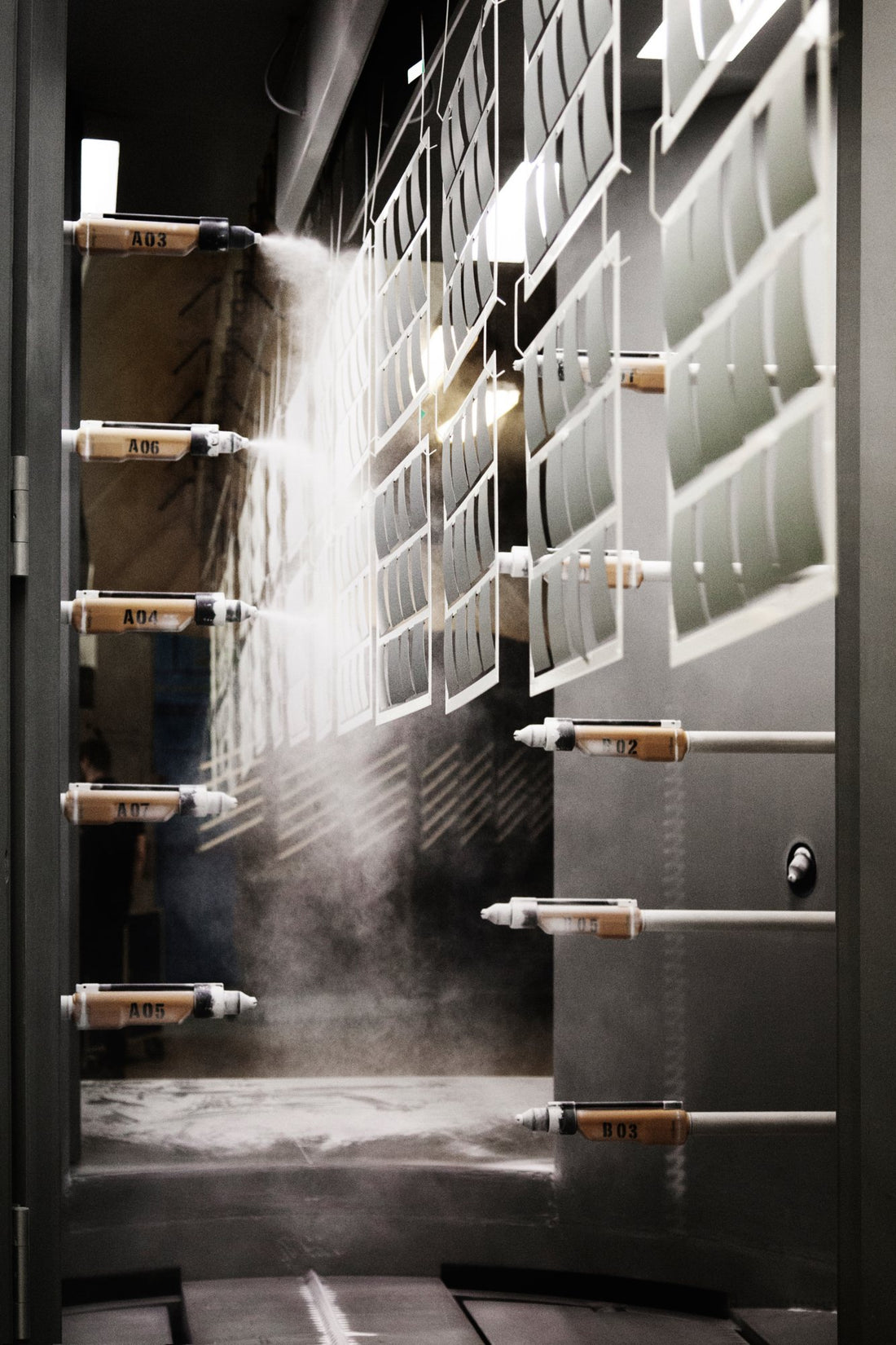 Powder coating line at the Louis Poulsen factory: spray nozzles coat hanging shades.