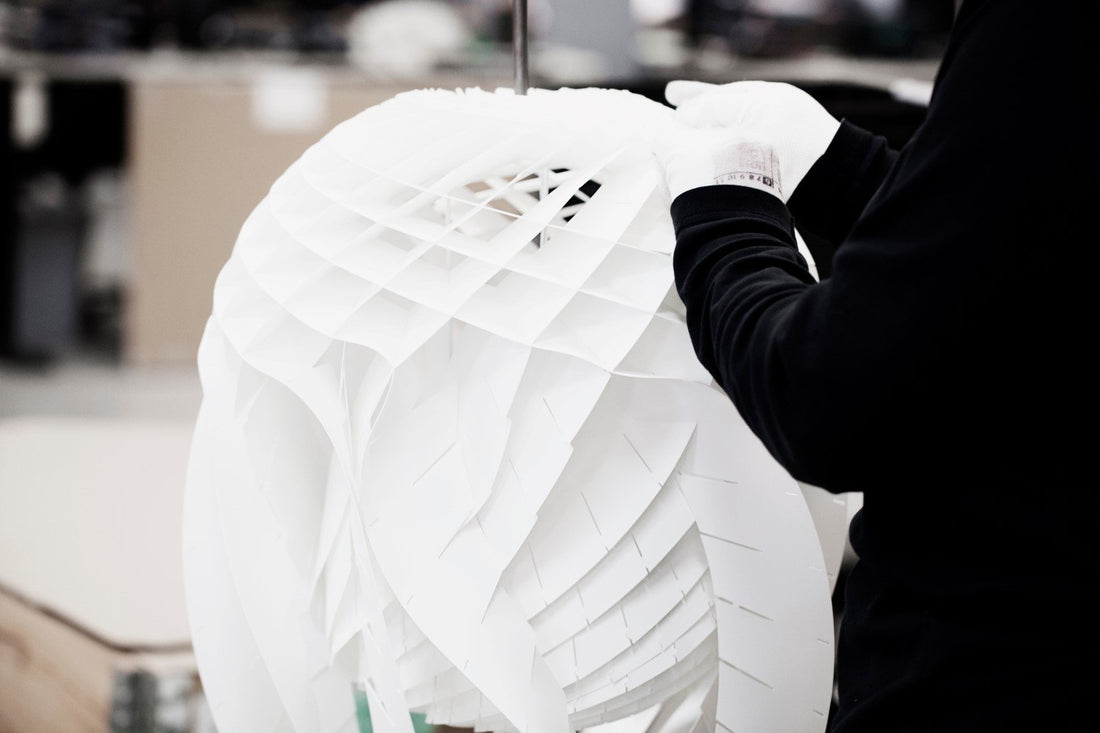 Gloved hands assemble the layered white shade of a Patera pendant.