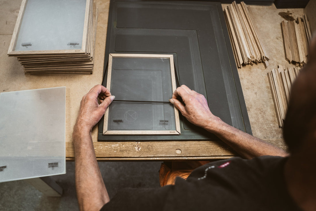 Hands assembling a wooden picture frame on the workbench.
