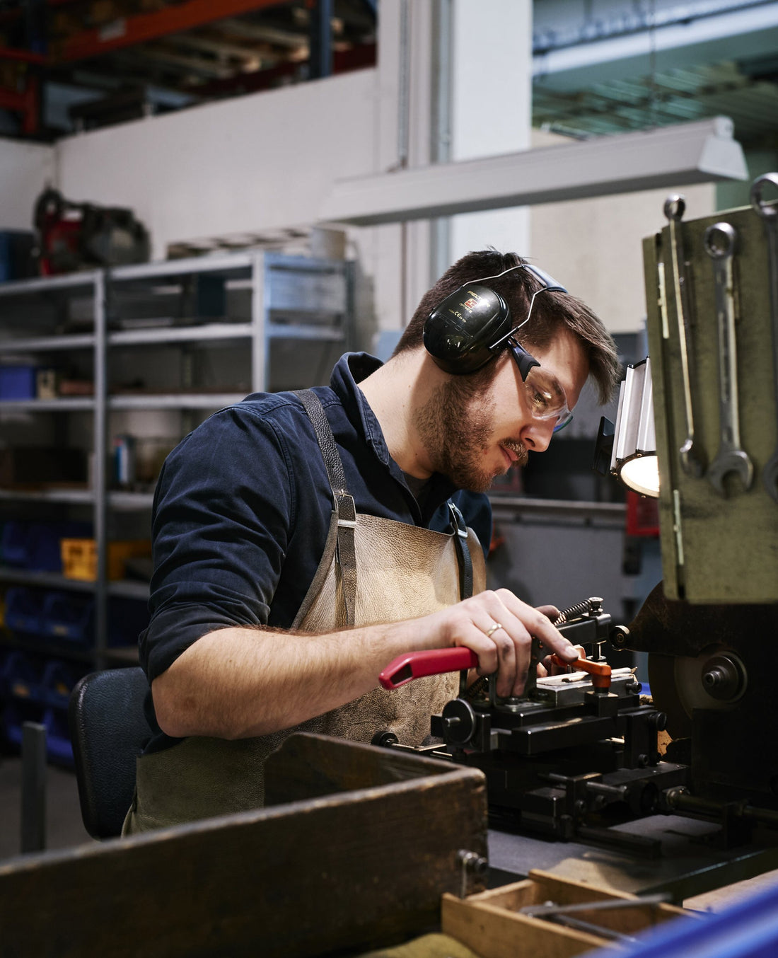 A worker with ear protection and leather apron clamps a piece into the grinding jig at the Mono factory in Mettmann.