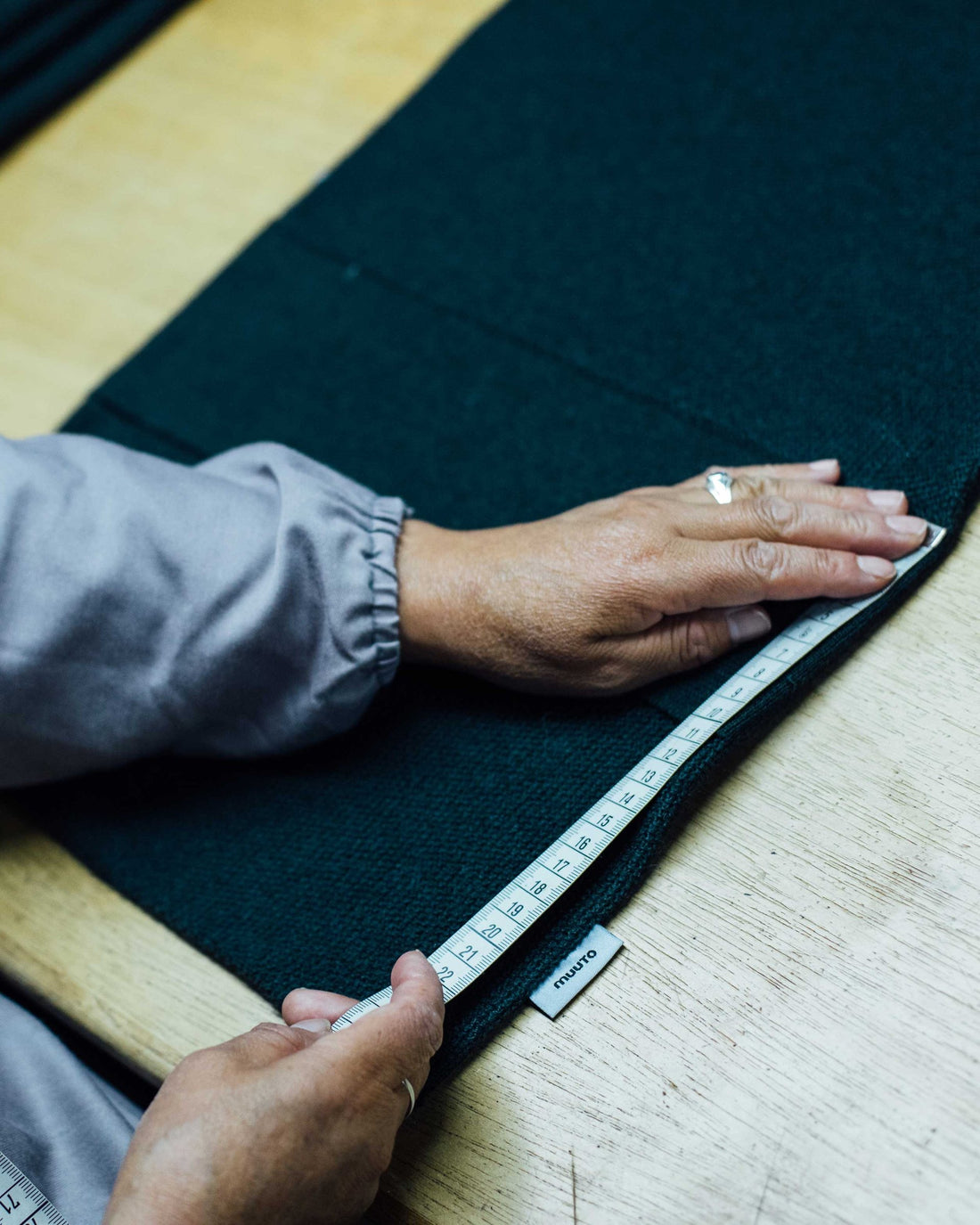 Hands measuring a piece of knitted wool fabric with a tape measure at the factory in La Paz.