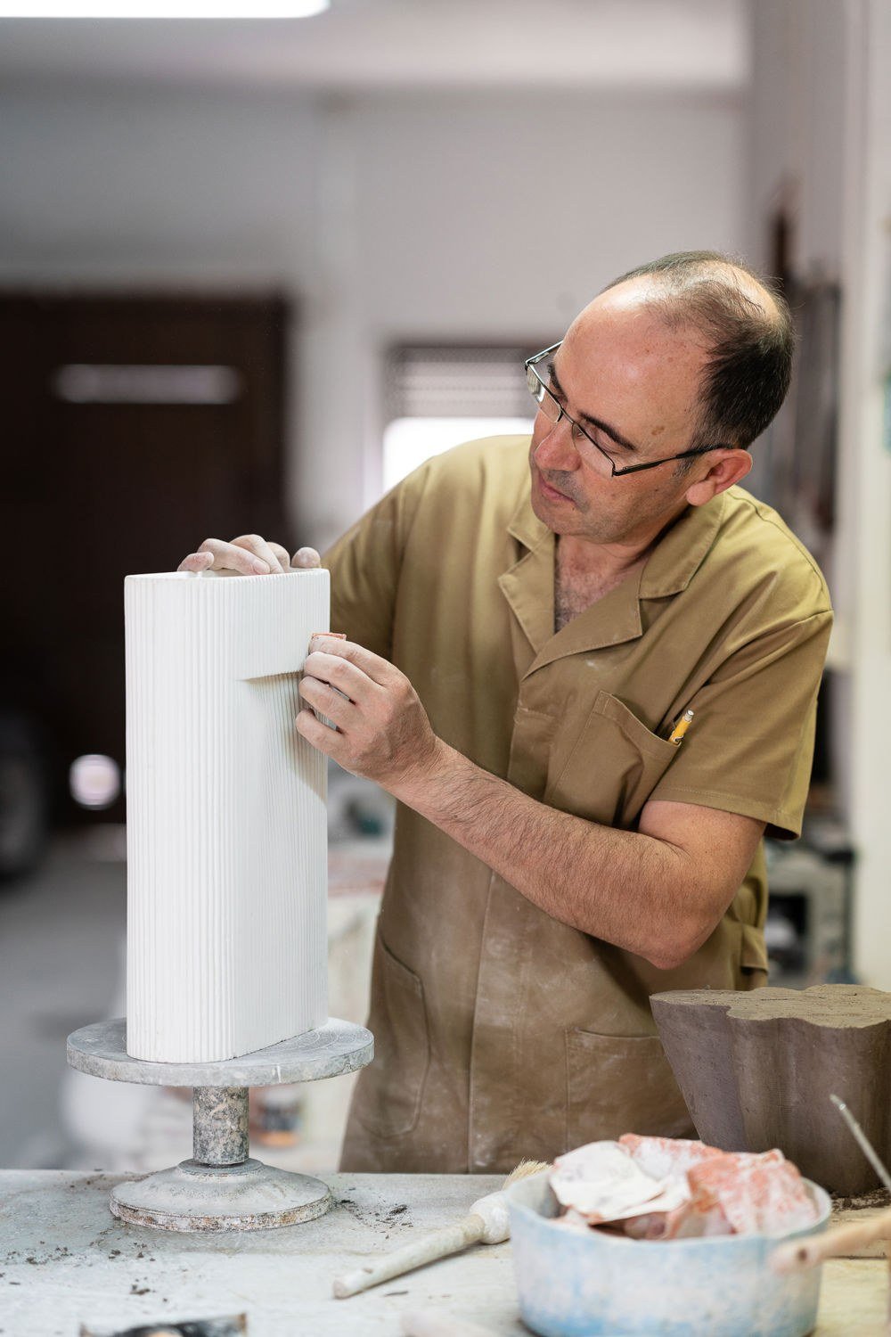 A mould maker in Portugal refining the plaster model of a ceramic vase in his workshop.