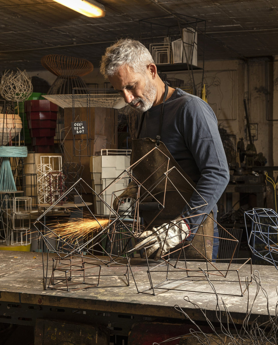 Antonino Sciortino grinds a welded wire frame at the workbench in his metal workshop.