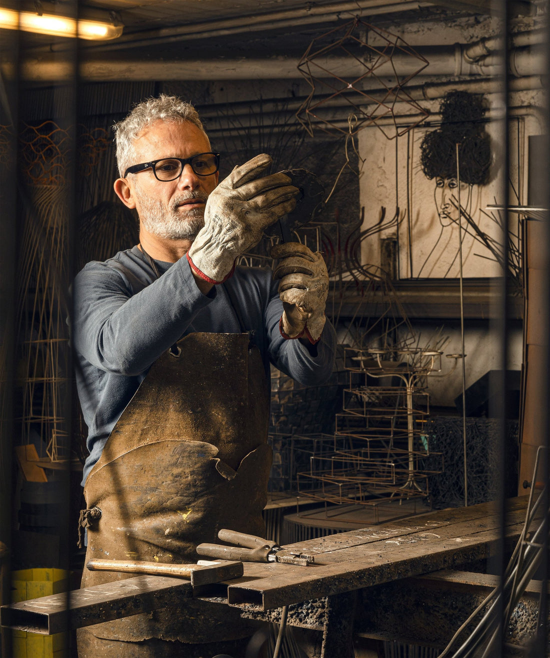 Antonino Sciortino bends a length of iron wire by hand in his workshop.
